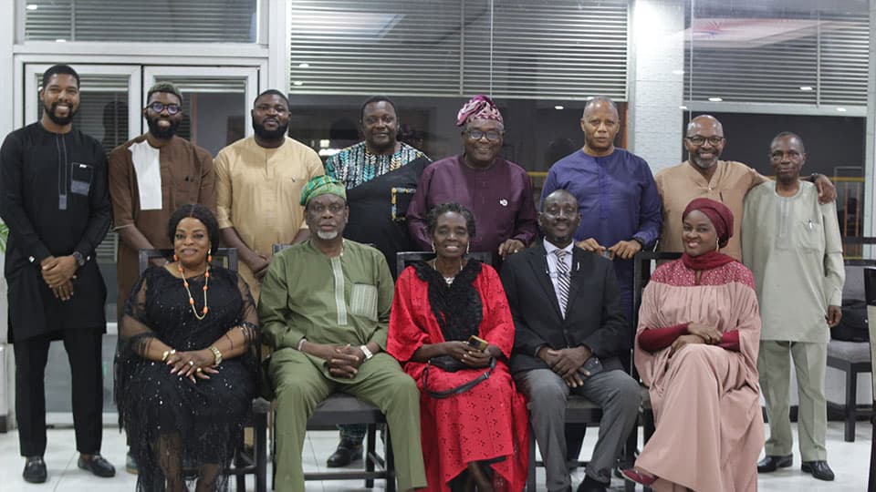 A group of thirteen alumni standing together and smiling at a dinner in Lagos, Nigeria.